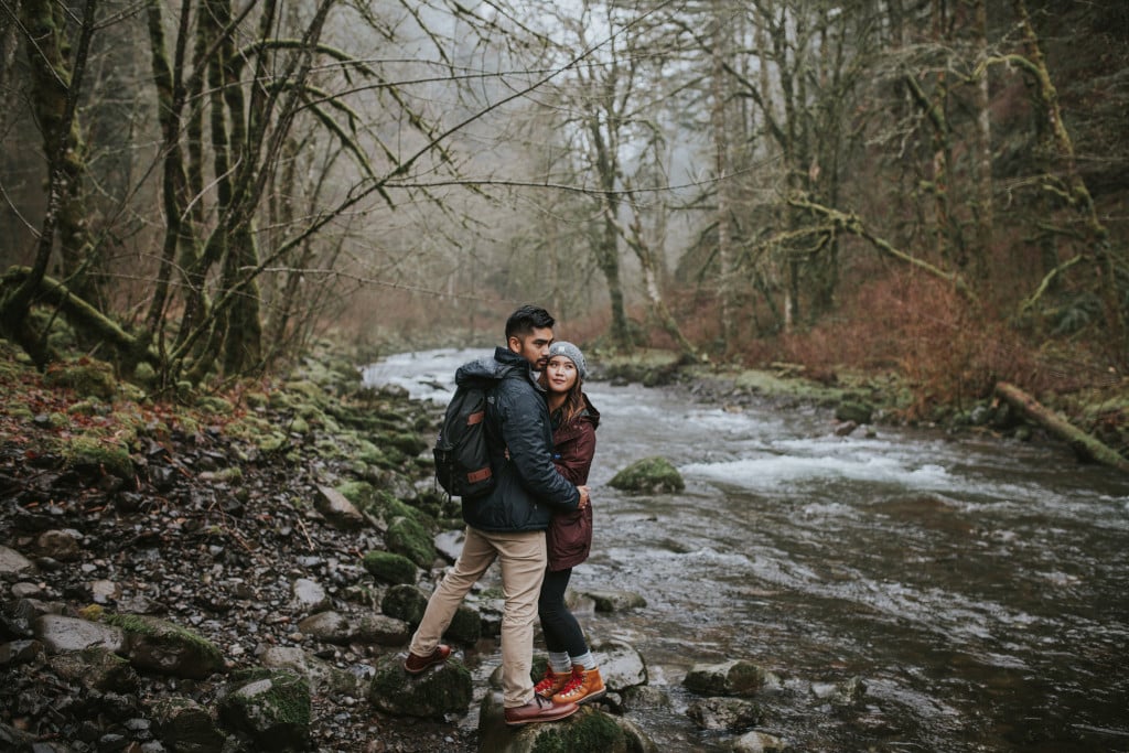 couple hiking by river wahclella falls by Marcela Pulido Portland Wedding Photographer