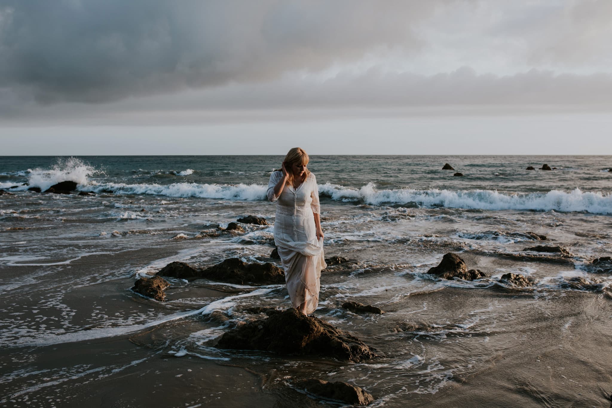 girl standing on rock at end of ocean El Matador Beach Engagement Marcela Pulido Portland Wedding Photographer