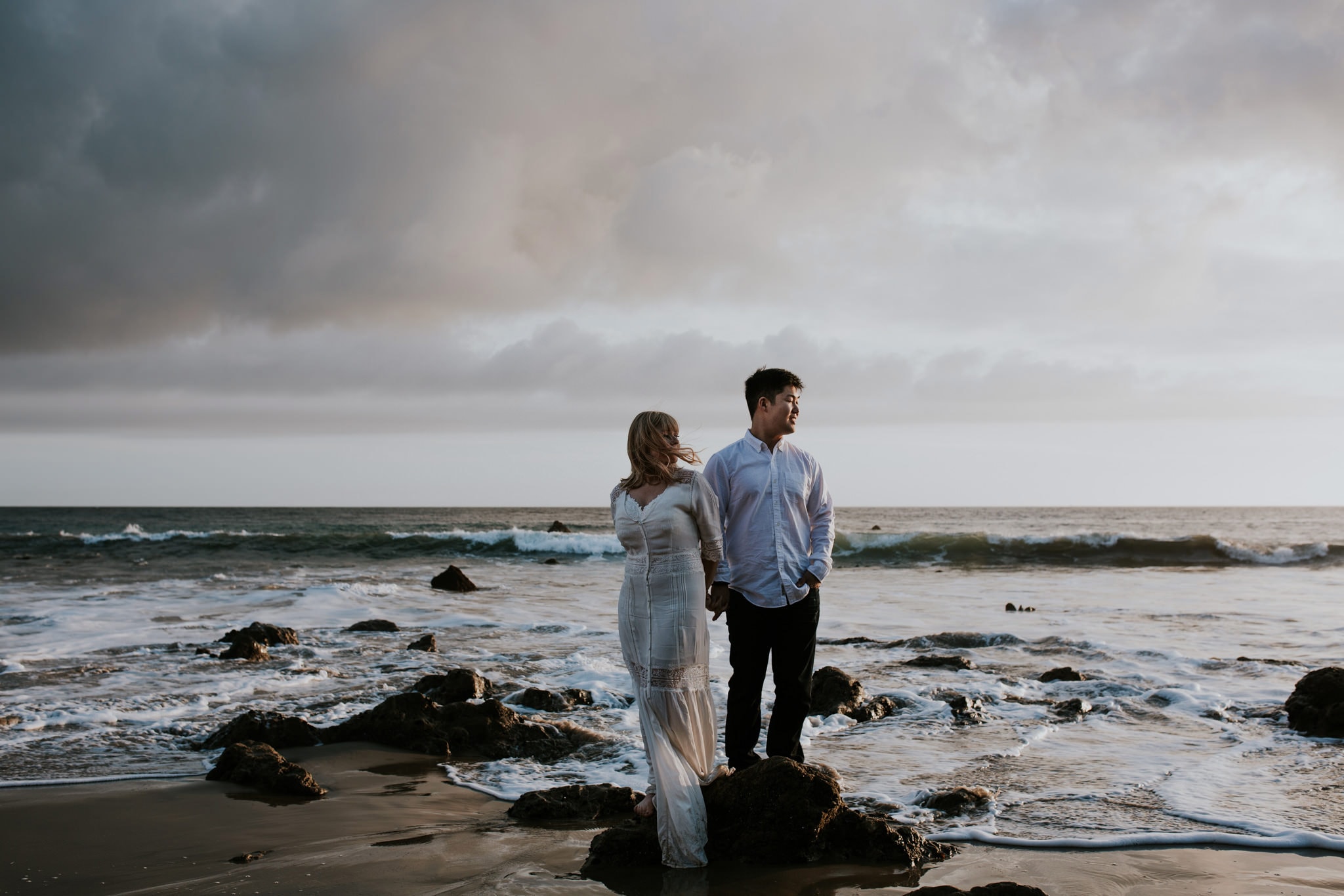 girl and guy on rock on ocean El Matador Beach Engagement Marcela Pulido Portland Wedding Photographer