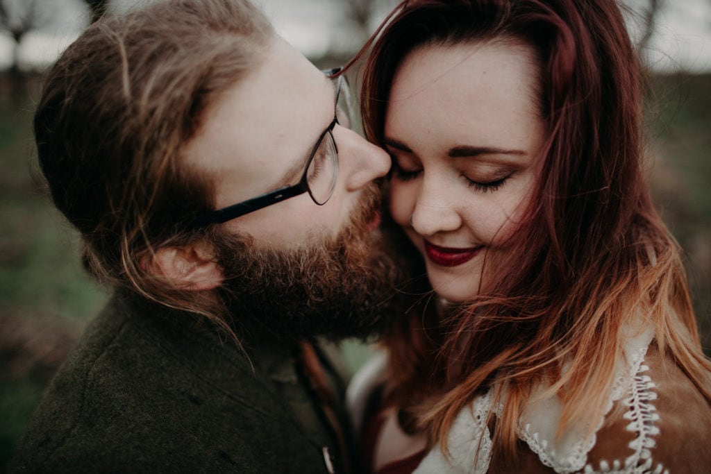 man kisses fiance on cheek close up Powell Butte Portland Engagement Photographer by Marcela Pulido Photography Portland Wedding Photographer