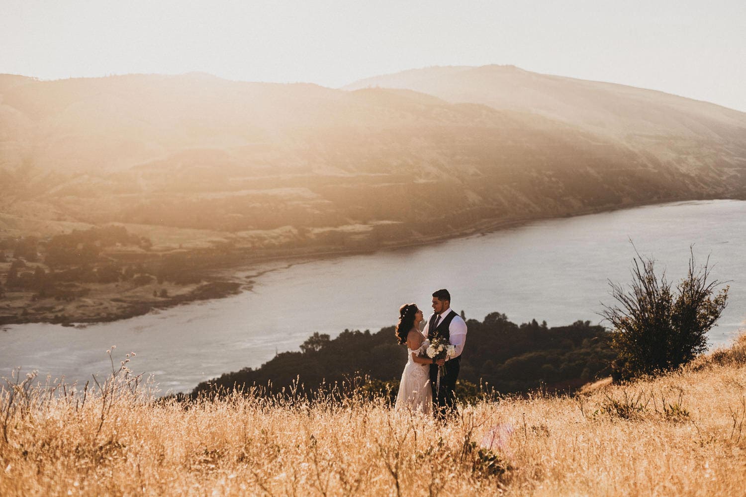 couple embrace with epic views of the Columbia River Gorge at sunset for golden hour as they elope in Oregon