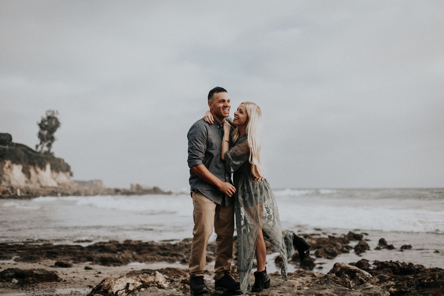 cute couple laughing foot popped up green dress blonde laguna beach engagement photographer