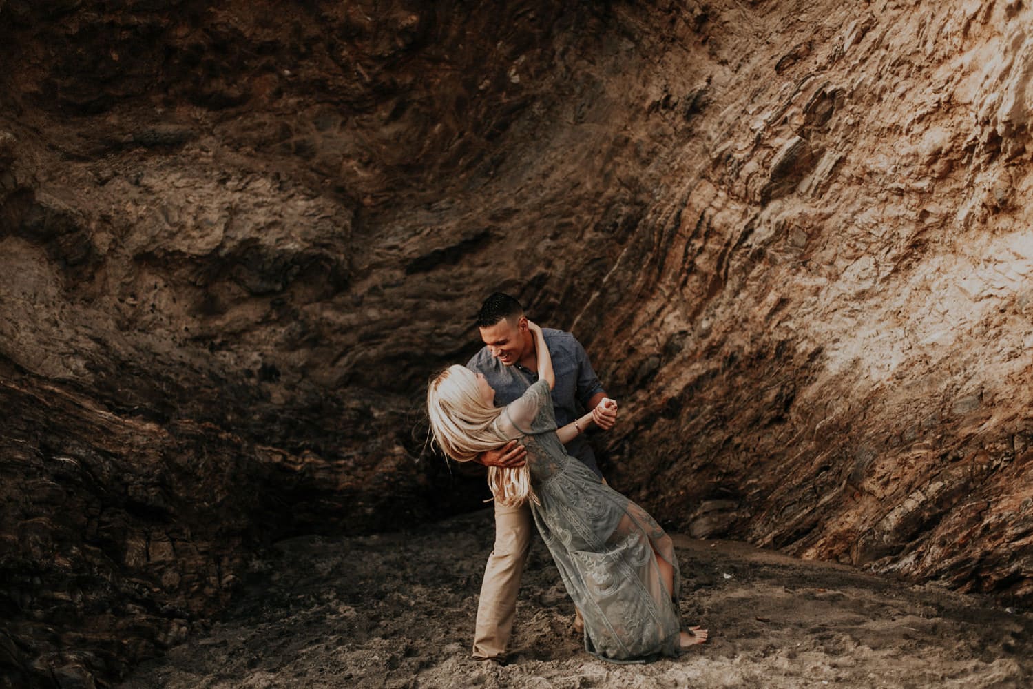 golden dip and kiss against cliff laguna beach engagement photographer