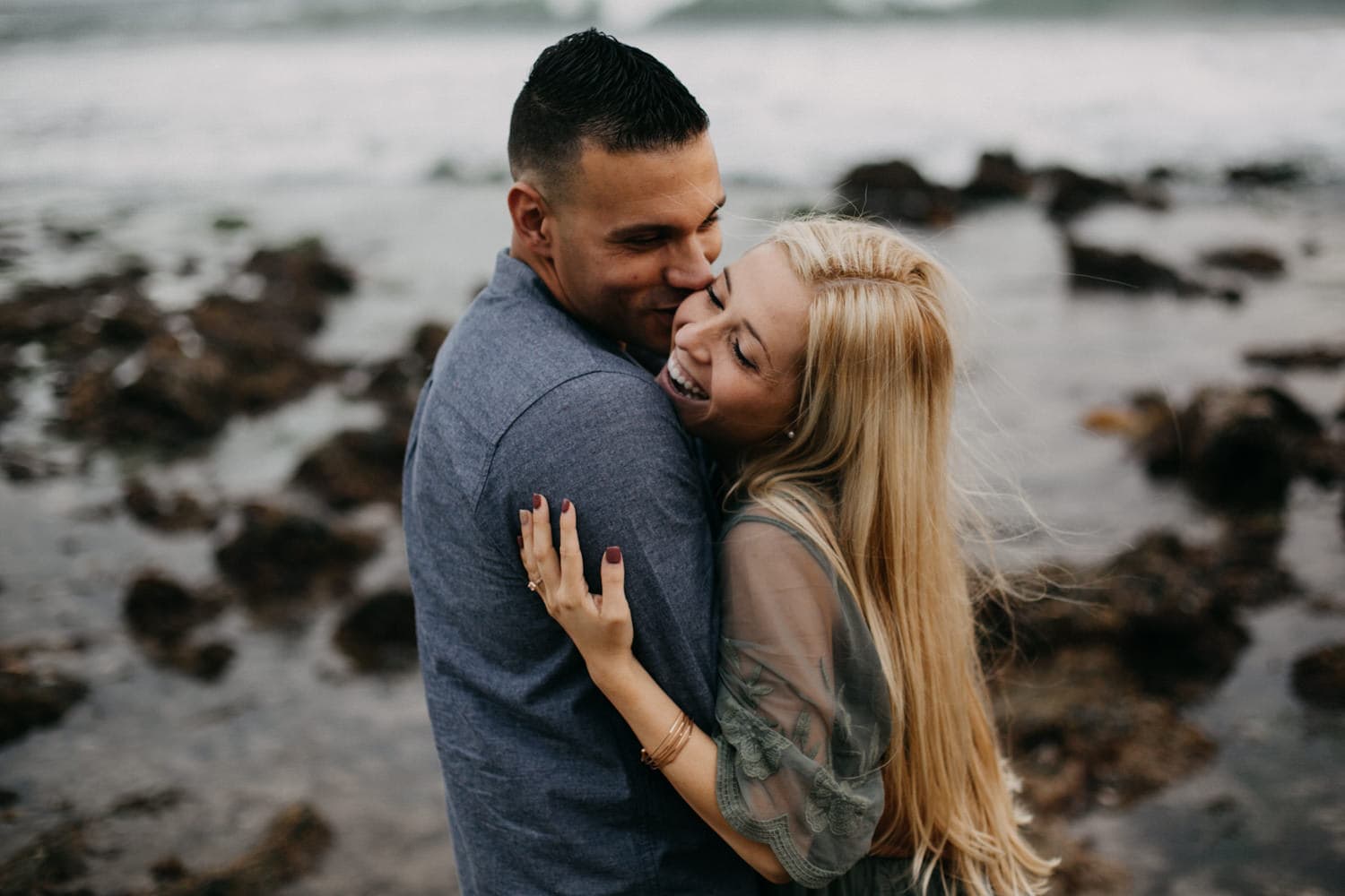cute blonde couple cuddling and laughing together laguna beach engagement photographer