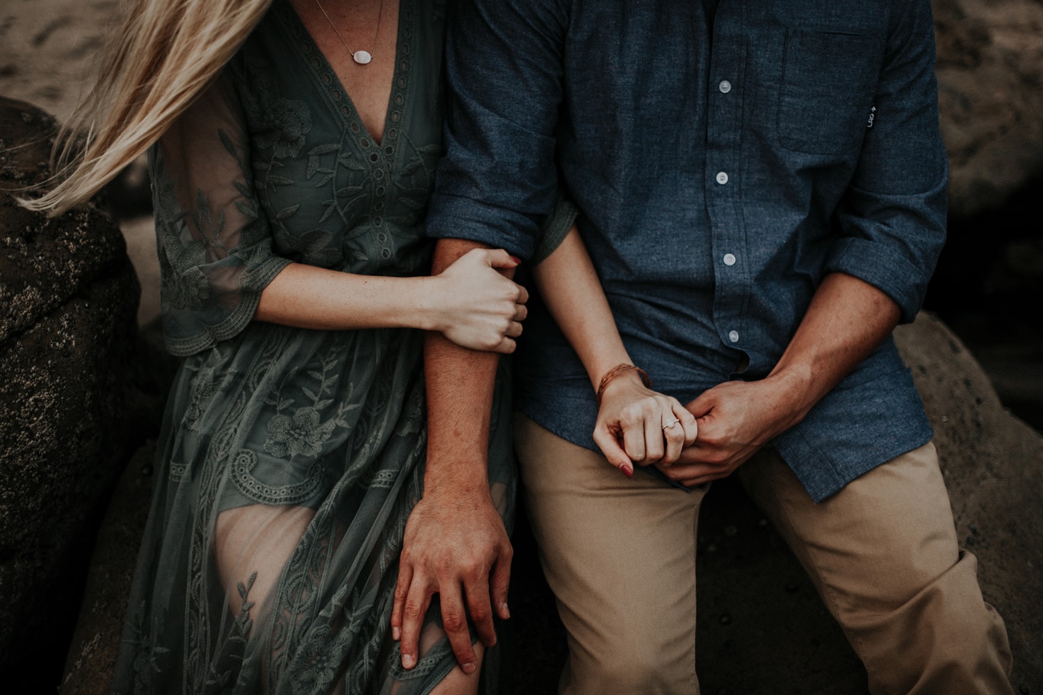 dark moody couple affectionately holding hands laguna beach engagement photographer