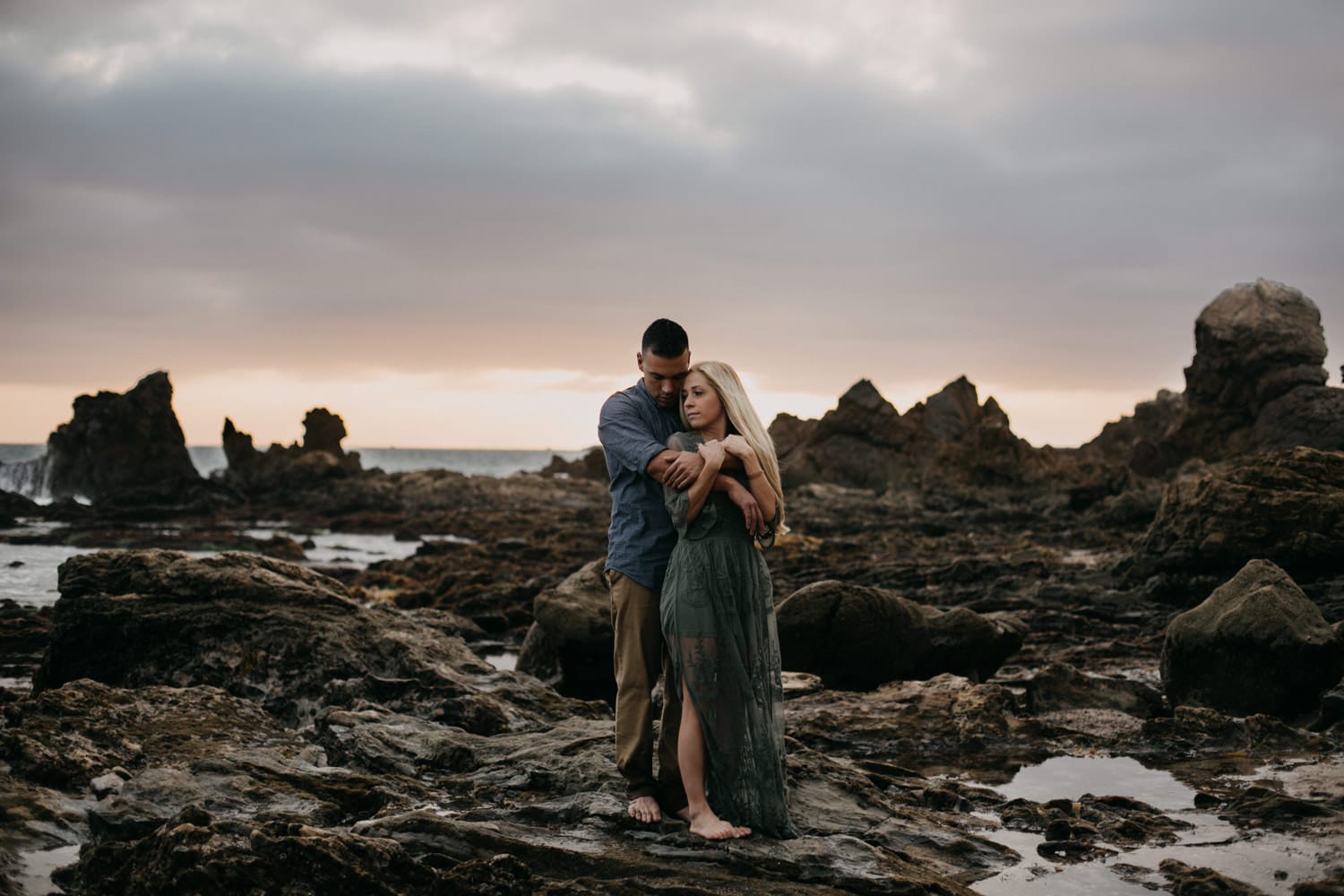 moody dark affectionate couple cuddling West Coast sunset laguna beach engagement photographer