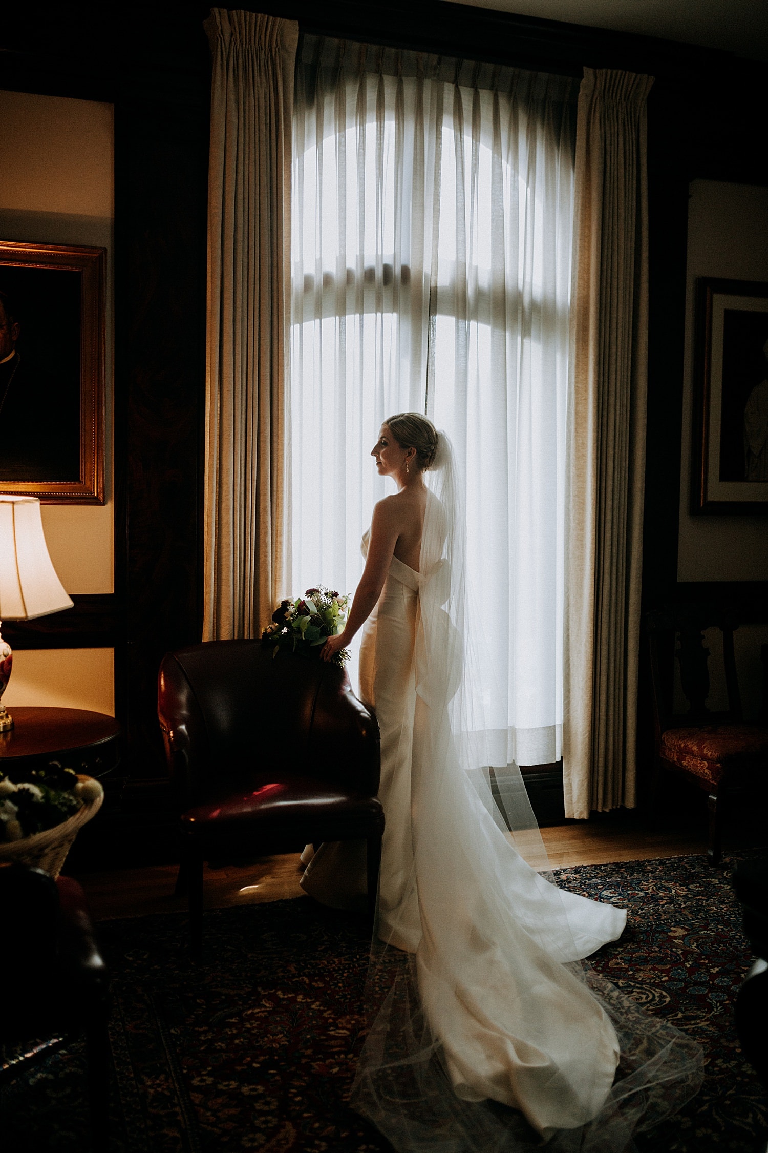 stunning dark and moody portrait of the bride standing in front of a window at St James Cathedral 415 Westlake Wedding by Marcela Pulido Seattle Wedding Photography