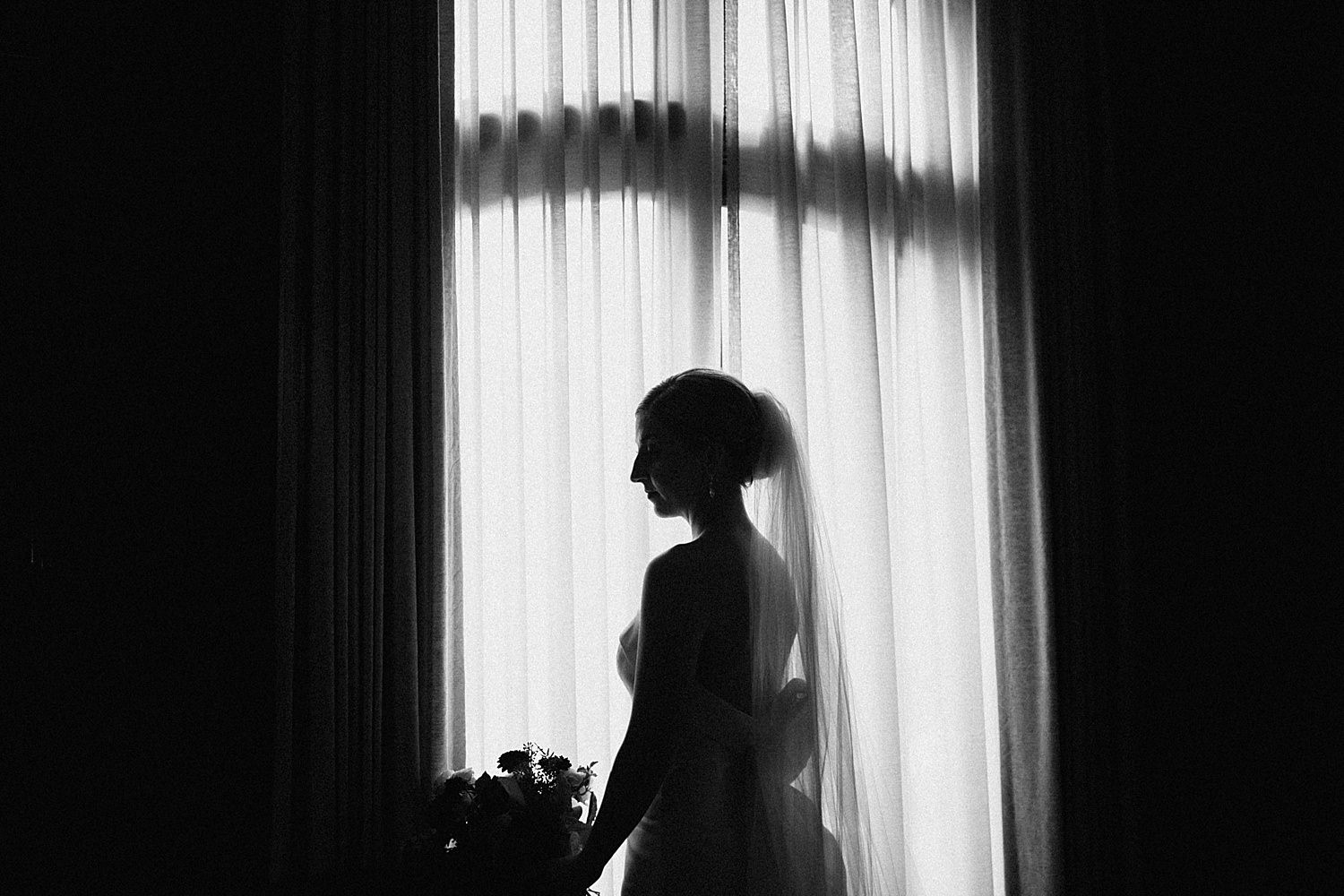 black and white dark moody silhouette portrait of the bride standing in front of the window at St James Cathedral 415 Westlake Wedding by Marcela Pulido Seattle Wedding Photography