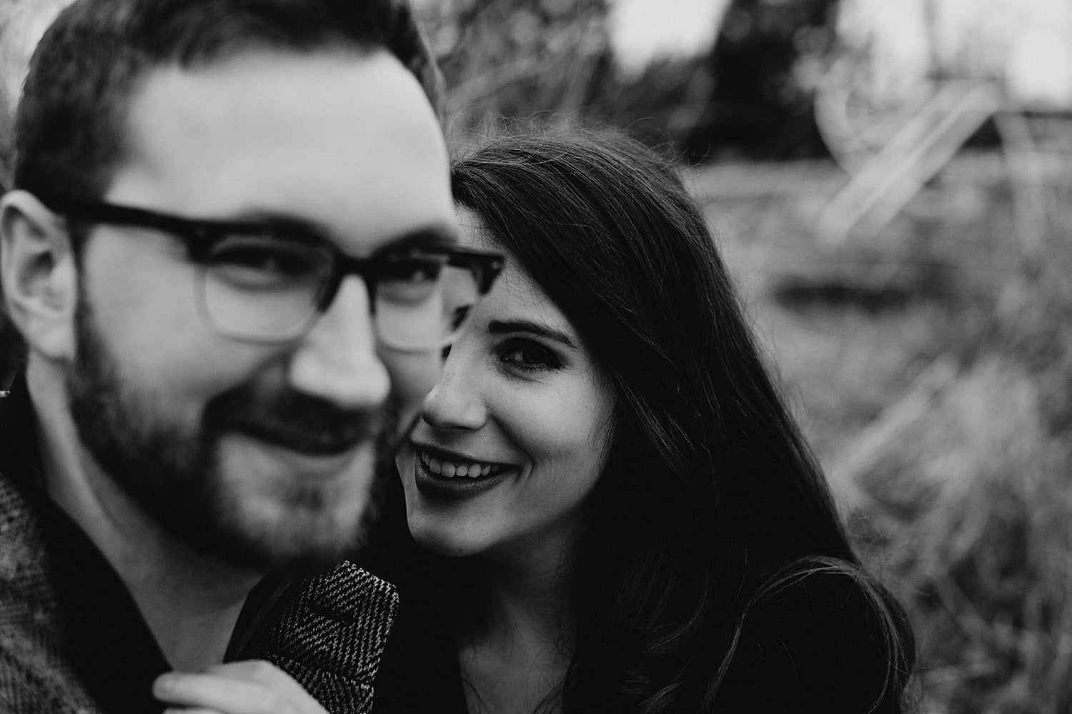 black and white portrait of a couple girl is smiling at the camera and the guy is out of focus Cooper Mountain Engagement session by Portland engagement photographer Marcela Pulido