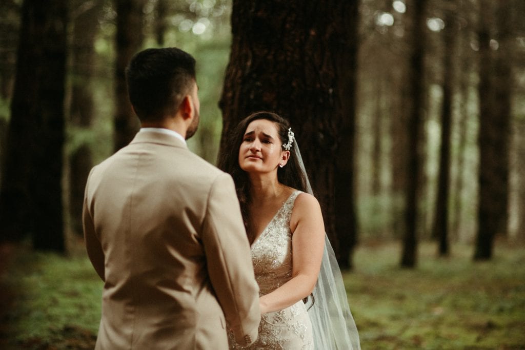 emotional bride looking at her groom with tears in her eyes in the middle of a forest ceremony captured by Marcela Pulido Photography Portland Oregon Wedding Photographer