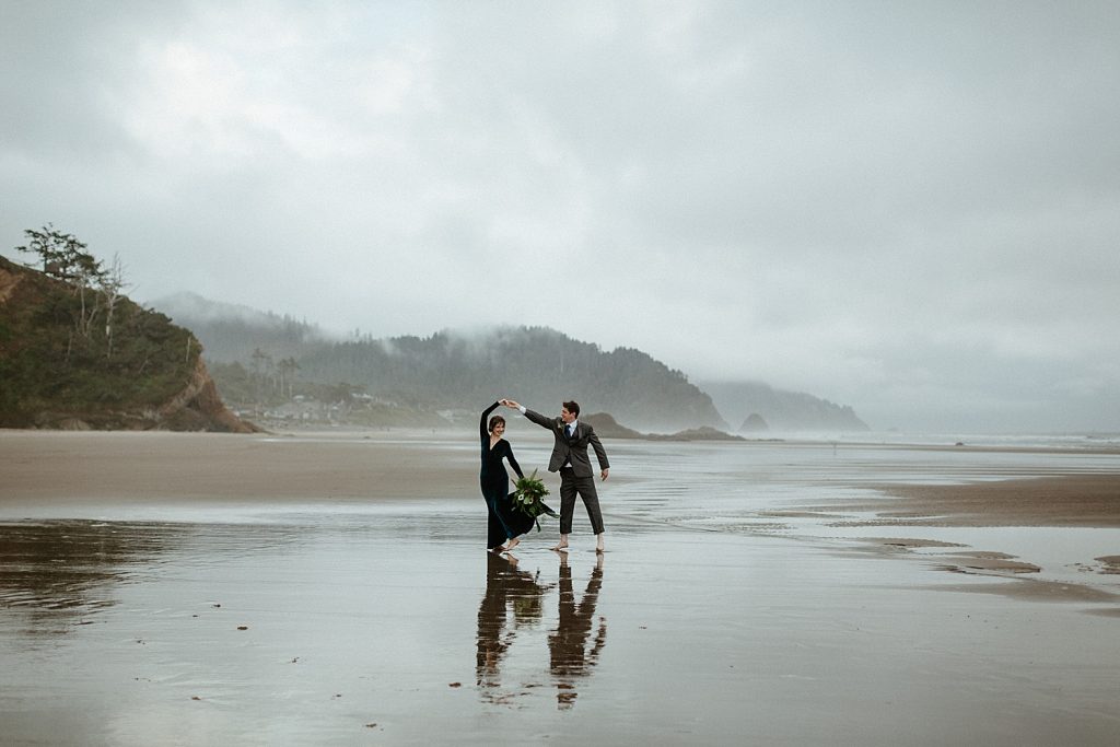 groom twirling his bride on a foggy moody oregon coast elopement hug point captured by marcela pulido photography portland oregon wedding elopement photographer