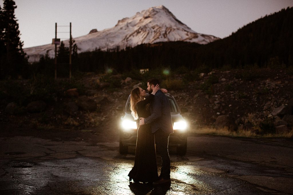couple dressed in black embracing in front of a snowy mt hood in oregon engagement