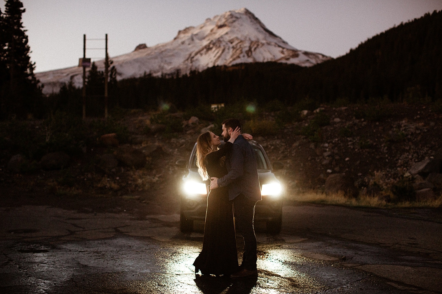couple dressed in black embracing in front of a snowy mt hood in oregon engagement