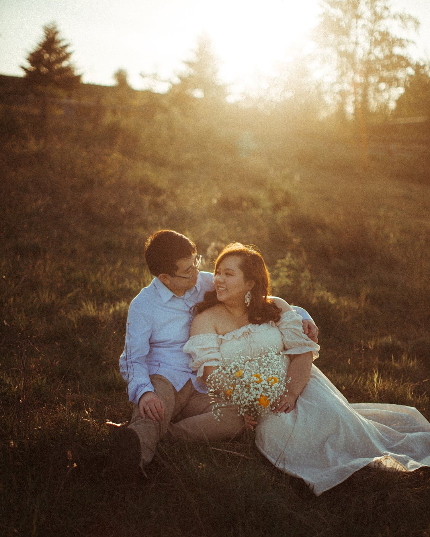 adorable asian couple sitting in a field during golden hour at powell butte park in portland oregon cottagecore engagement session