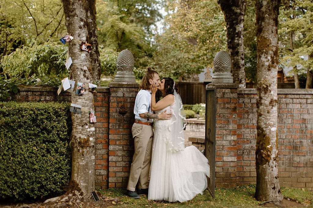 bride and groom kiss at this brick fence at their french country cottage wedding in lakewood washington