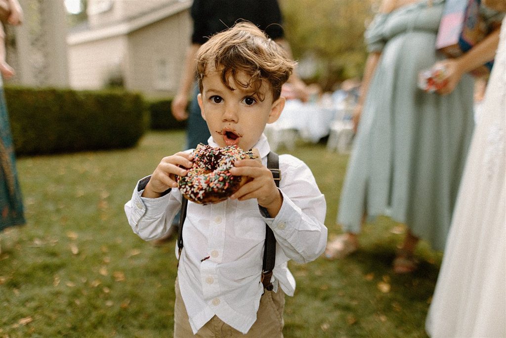 adorable boy eating a donut with chocolate on his face